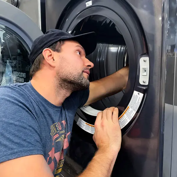 Professional technician repairing a washer in a home kitchen